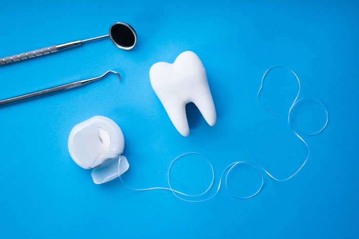 dental elements dental floss and toy tooth on a blue background